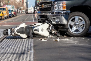 A wrecked motorcyle under a pick-up truck, where a Motorcycle Accidents Lawyer in East Peoria IL is needed
